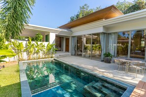 Ein modernes Haus mit Schwimmbad, großen Fenstern und einer Terrassenfläche.