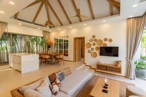 A modern living room with a sofa, coffee table, and a TV mounted on the wall. - Private Pool Villa in the Heart of Bang Tao (ต.เทพกระษัตรีย์)