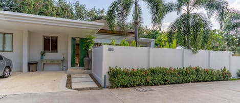 A modern house with a white exterior, a garage, and a well-maintained garden with red flowers.