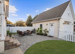 A residential backyard with a patio, outdoor furniture, and a white fence.