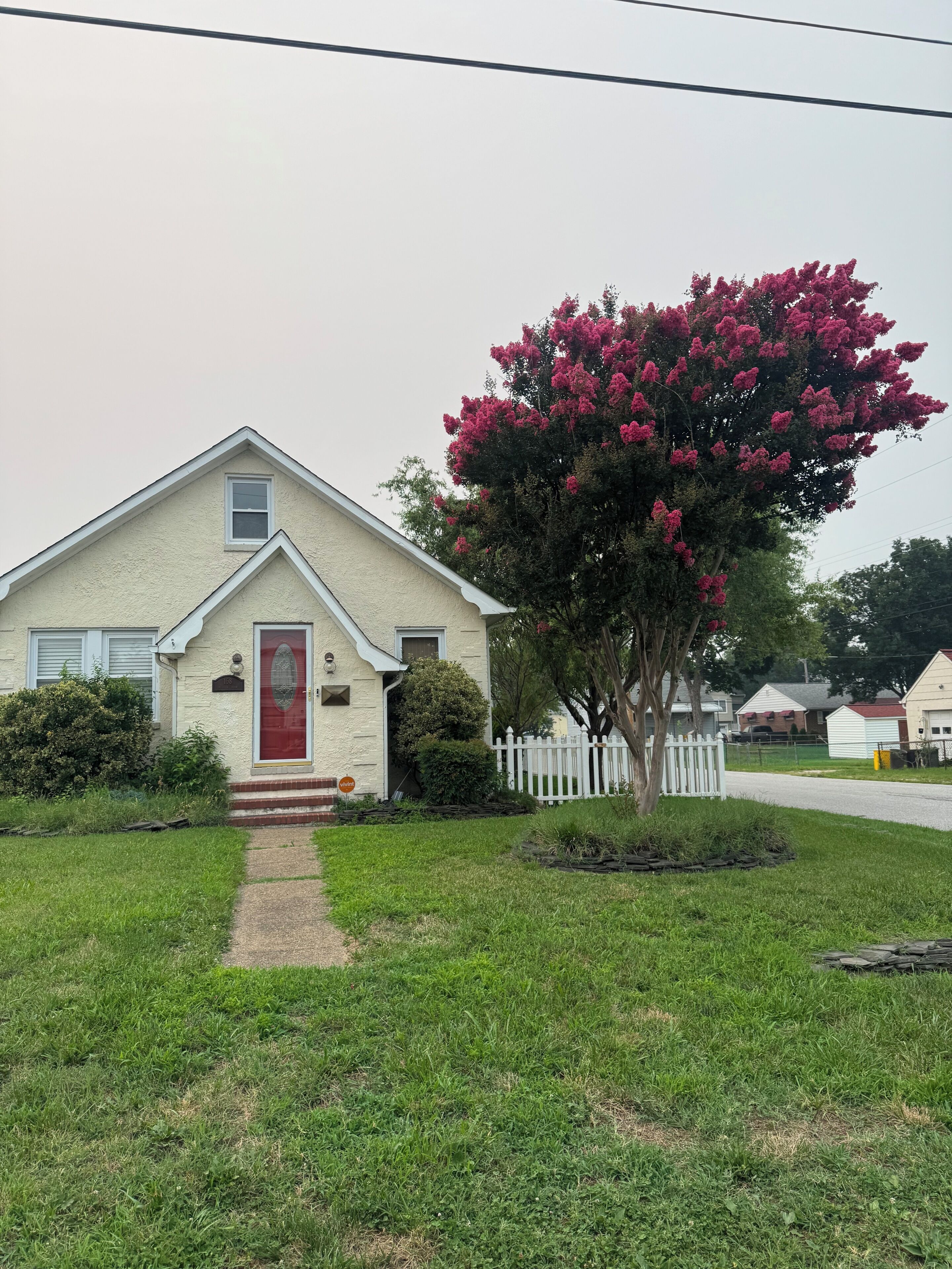 A single-story house with a red door and a small front yard.