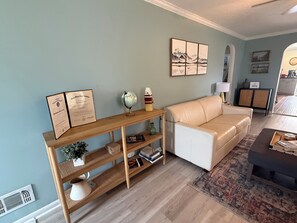 A living room with a beige sofa, a wooden console table with certificates, a globe, and a lamp.