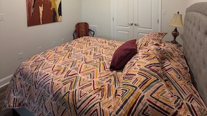 A bedroom with a bed, a ceiling fan, a door, and a wall-mounted lamp.