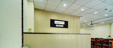 Una zona de recepción con un letrero que dice 'PALETTE' y un sofá verde.