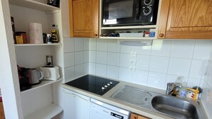 Eine kleine Küche mit Mikrowelle, Herd, Geschirrspüler und Holzschränken.