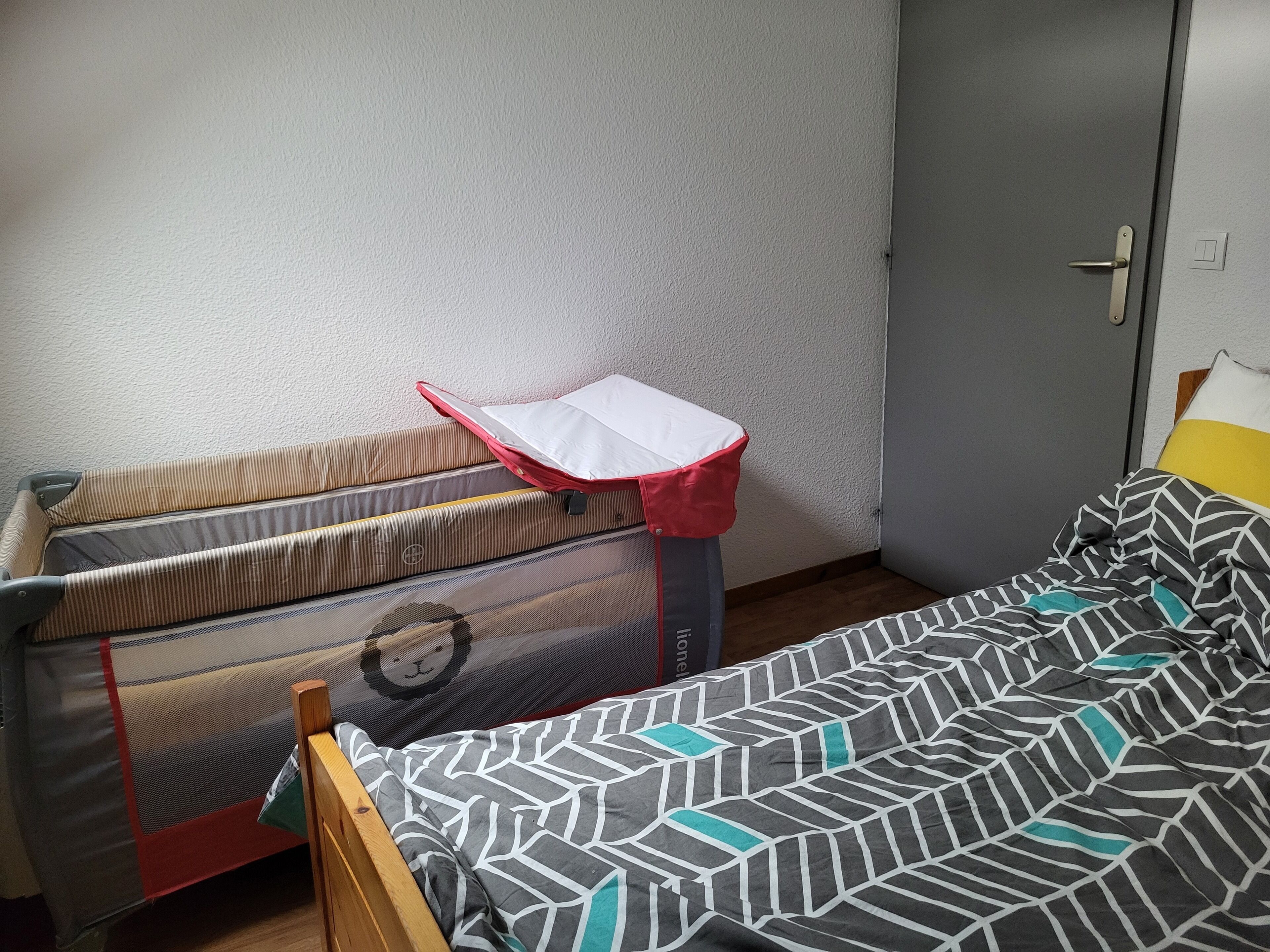 A room with a bed, a suitcase, and a door.