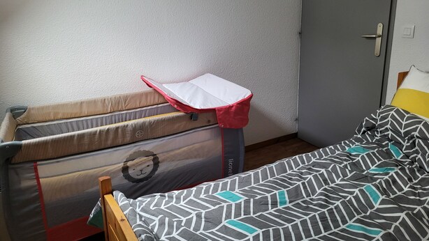 Ein Zimmer mit einem Bett, einem Koffer und einer Tür.