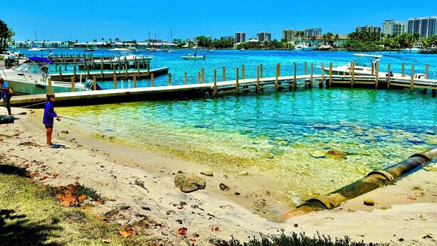 A marina with boats docked, a pier extending into the water, and a city skyline in the background. - Rent The Crafty Mermaid, 2-bedroom house, yard, near Blue Heron dive area (West Palm Beach)