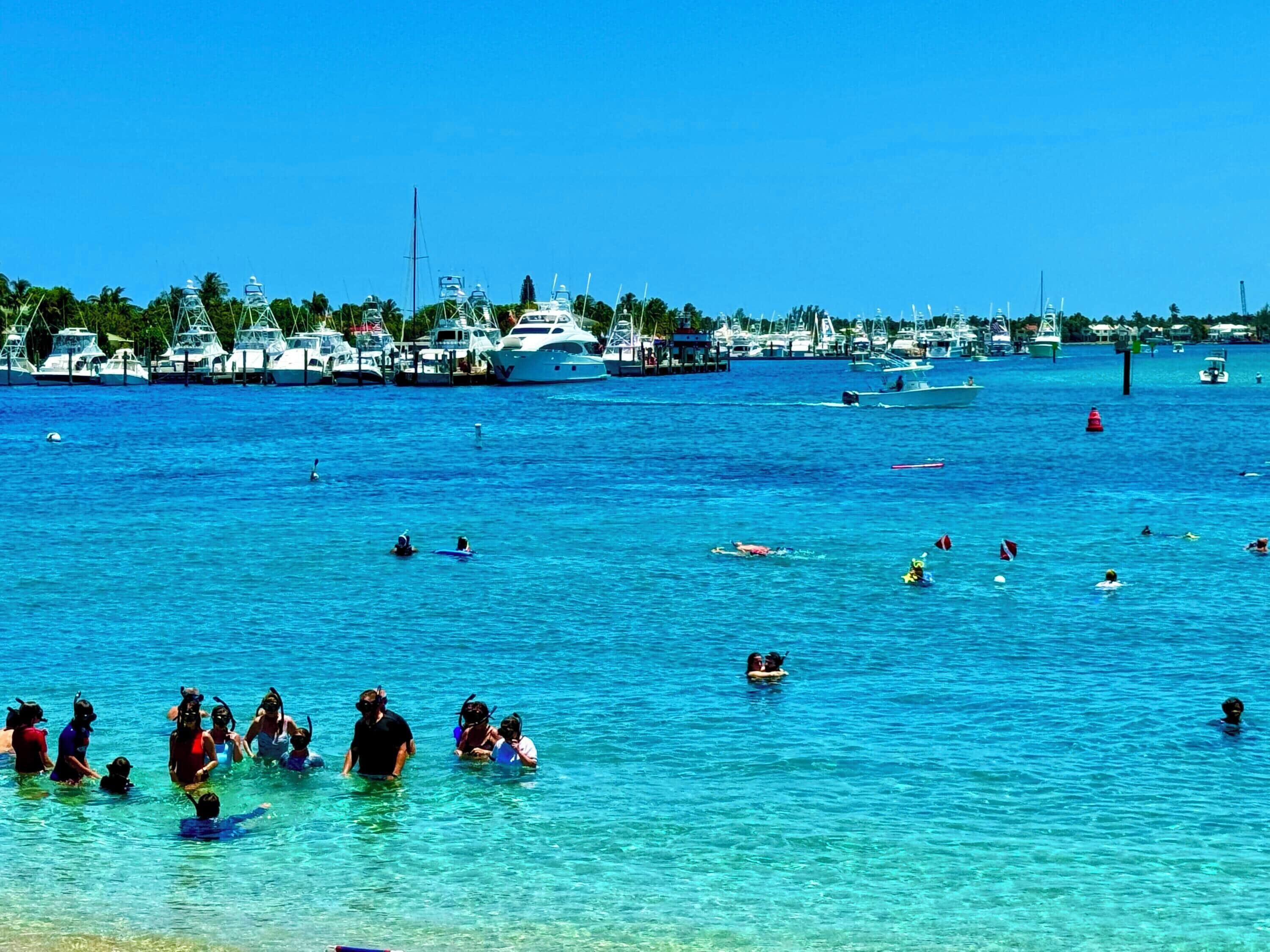 Un port de plaisance avec des bateaux amarrés et des gens qui se baignent dans l’eau.