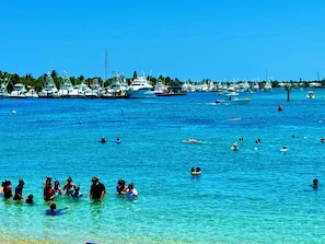 Ein Yachthafen mit vertäuten Booten und badenden Personen im Wasser.