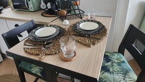 Une table à manger dressée avec des assiettes, des couverts et un verre.