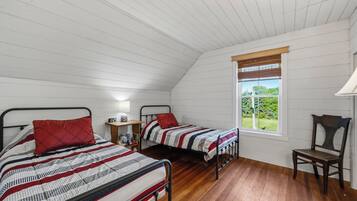 Una camera da letto con due letti, pavimento in legno, una finestra con vista e un comodino con una lampada.