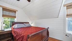 Una camera da letto con un letto in legno, un comodino, una lampada e una finestra con persiane.
