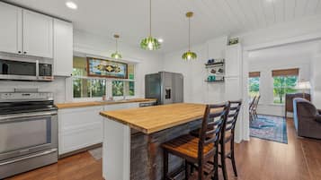 A modern kitchen with white cabinetry, a wooden island, and stainless steel appliances.