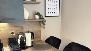 Une cuisine moderne avec une table en bois, des chaises noires et une décoration murale sur le thème du café.