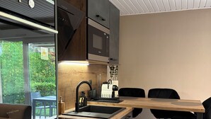 Une cuisine moderne dotée d’appareils électroménagers intégrés, d’un plan de travail en bois et d’un coin repas avec des chaises noires.