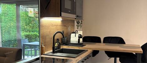 A modern kitchen with built-in appliances, a wooden countertop, and a dining area with black chairs.