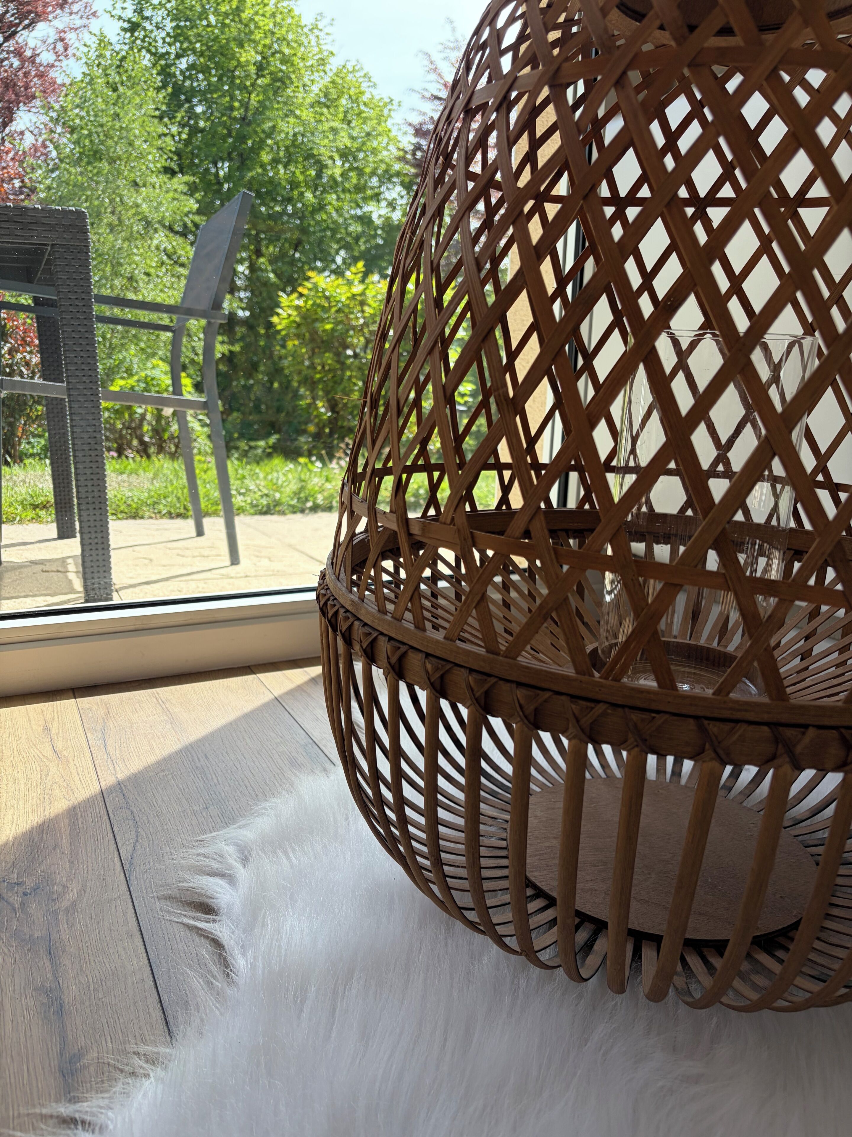 A wicker chair with a woven backrest and a wooden floor.