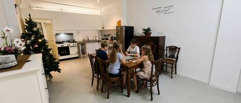 A modern kitchen with white cabinets, a dining table with wooden chairs, and a ceiling fan.