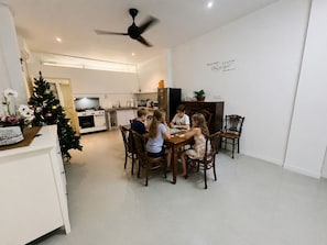 A modern kitchen with white cabinets, a dining table with wooden chairs, and a ceiling fan.
