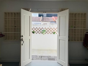 An open door leading to a courtyard with a tiled floor, a lattice fence, and a view of buildings in the background. - Georgetown Kyash House 23 (George Town)