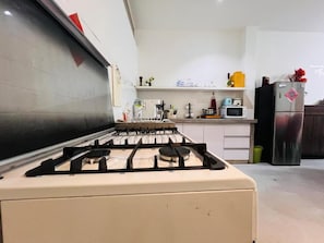 A kitchen with a gas stove, microwave, and refrigerator.