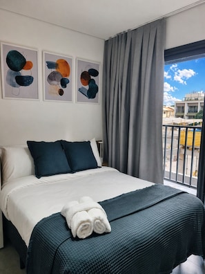 A hotel room with a bed, grey curtains, and artwork on the wall. - Studio Brooklin, EXPO (São Paulo)