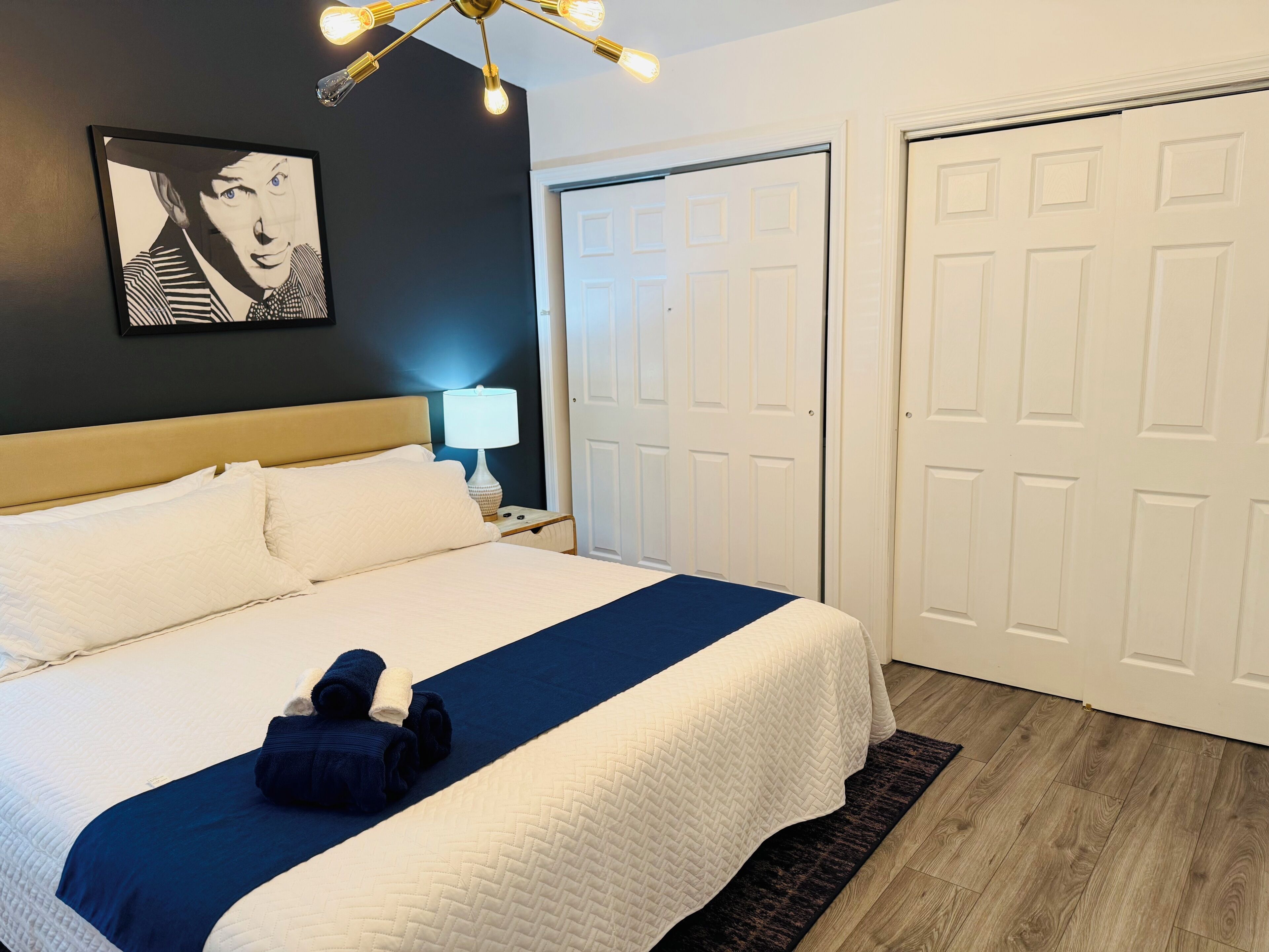 Ein ordentlich gemachtes Bett mit einer blau-weißen Bettdecke, einem Kopfteil und einer Nachttischlampe.