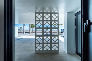 A view through a doorway with a decorative screen, leading to an outdoor area with a concrete floor and a clear sky.