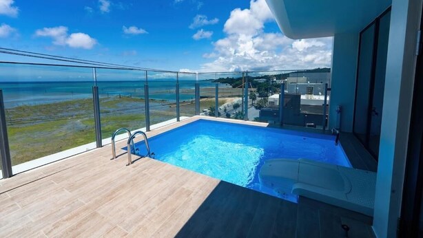 Piscina no terraço com vista clara do oceano e edifícios ao redor.