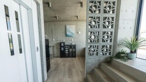 Um interior moderno com piso de madeira, escada, divisória decorativa e um vaso com planta.