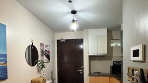 Eine kompakte Küche mit Mikrowelle, kleinem Kühlschrank und Holzschränken. Es gibt einen Essbereich mit Tisch und Stühlen.