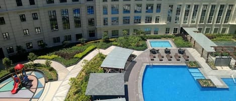 A residential building with a swimming pool, a children's play area, and a landscaped garden.