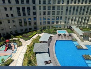 Un immeuble résidentiel doté d’une piscine, d’un espace de jeux pour enfants et d’un jardin aménagé.