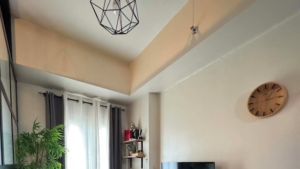 Ein modernes Wohnzimmer mit einer Couch, einem Fernseher, einem Esstisch und einer Pflanze.