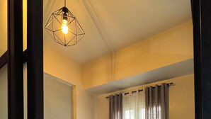 Ein Hotelzimmer mit einem Bett, einer Weltkarte als Wandbild und einer geometrischen Leuchte.