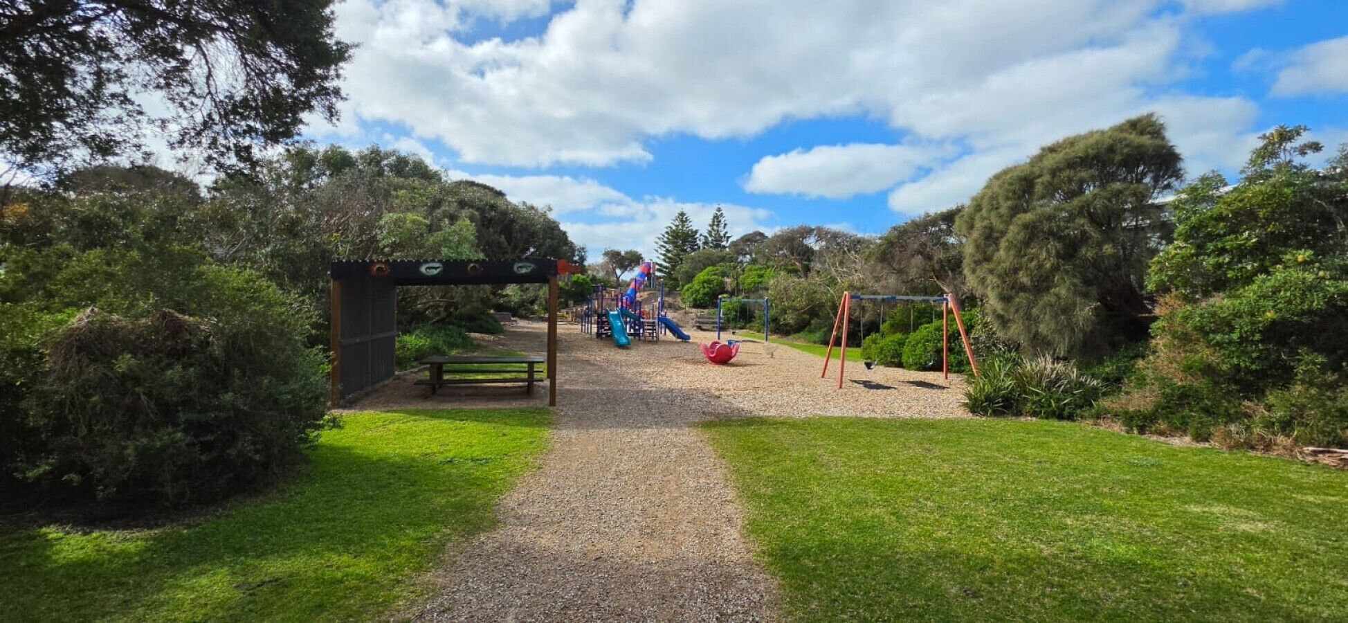 A pathway leading to a playground with a slide and swings.
