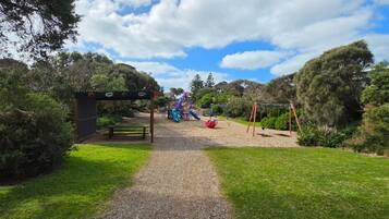 A pathway leading to a playground with a slide and swings.