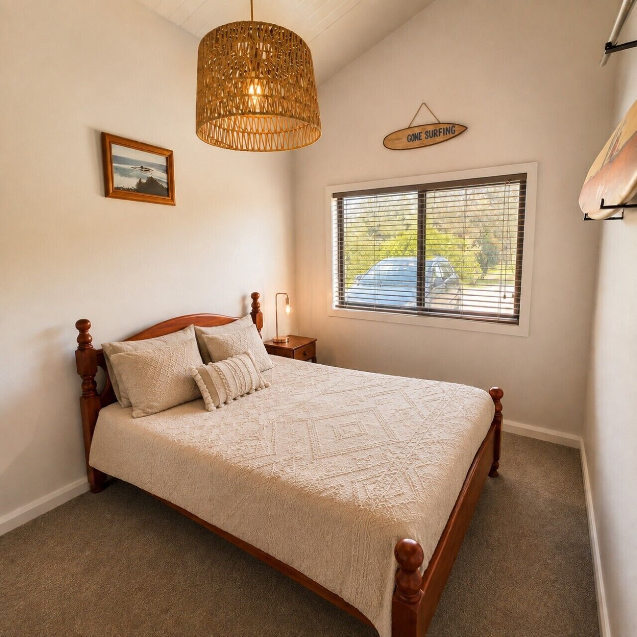A bedroom with a wooden bed, a hanging light fixture, a window with blinds, and a sign on the wall.