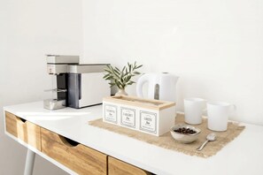 Eine Küchenarbeitsplatte mit einer Kaffeemaschine, einer Teedose und zwei weißen Tassen.