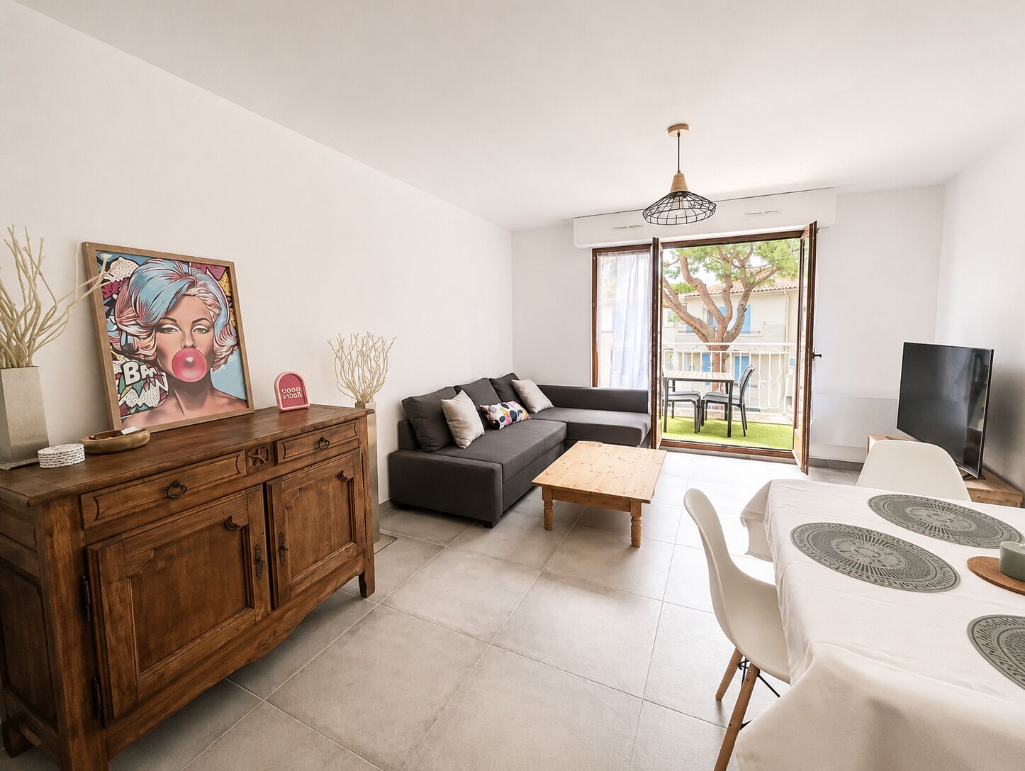 A modern living room with a sofa, coffee table, and a dining area with a TV and table.