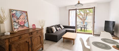 A modern living room with a sofa, coffee table, and a dining area with a TV and table.