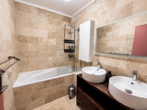 Ein modernes Badezimmer mit Badewanne, zwei Waschbecken, einem Spiegel und einem Handtuchhalter.
