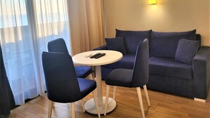 A room with a blue sofa, two chairs, a small round table, and an air conditioning unit mounted on the wall. - Orbi City 2-bedroom apartment in Batumi with air conditioning (Batumi)