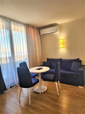 A room with a blue sofa, two chairs, a small round table, and an air conditioning unit mounted on the wall. - Orbi City 2-bedroom apartment in Batumi with air conditioning (Batumi)