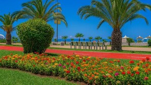 A landscaped area with palm trees, a pathway, and a flower bed. - Orbi City 2-bedroom apartment in Batumi with air conditioning (Batumi)