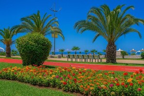 A landscaped area with palm trees, a pathway, and a flower bed. - Orbi City 2-bedroom apartment in Batumi with air conditioning (Batumi)