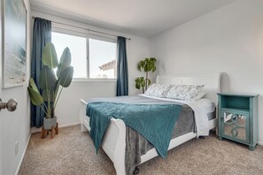 A bedroom with a bed, a window with curtains, a potted plant, and a nightstand. - Main Level Primary Suite PRIVATE Mtn View Yard,
Pool Spa Firepit BBQ 15 mn Strip (Henderson)