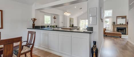 A spacious kitchen with a central island, white cabinetry, and a chandelier.