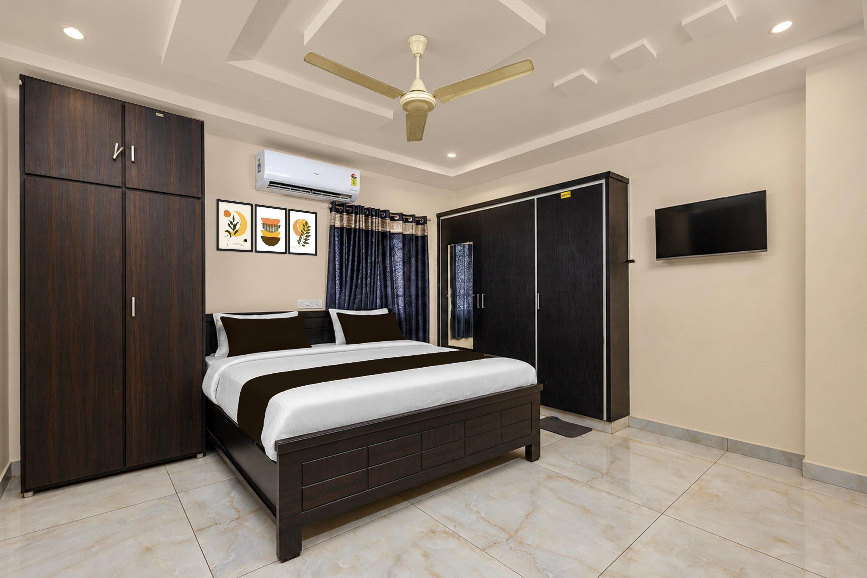 A bedroom with a bed, wardrobe, ceiling fan, air conditioning unit, and a TV.